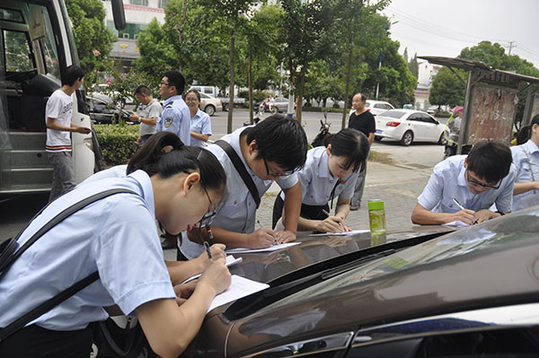 志愿者们接着停放的轿车填写献血单.JPG